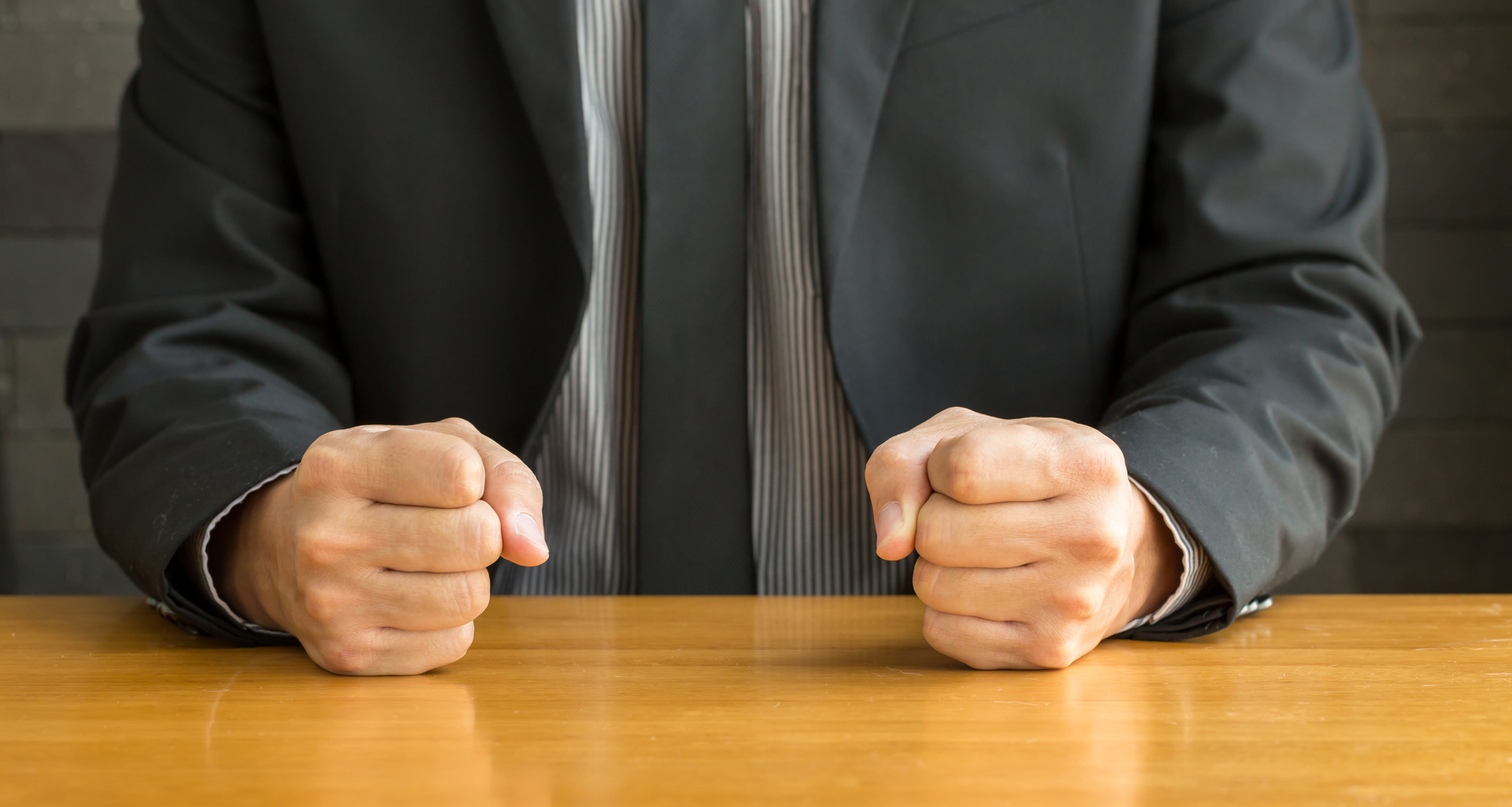 Businessman with clenched fist on the desk at office
